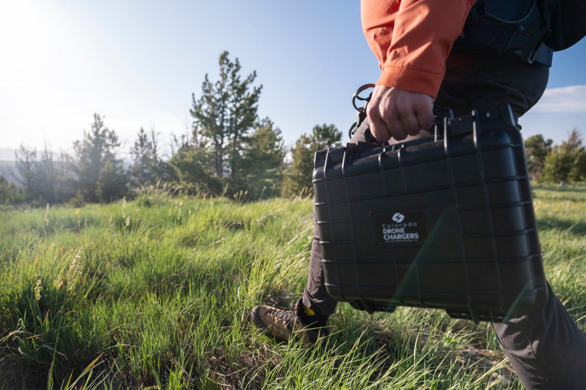 Drone pilot carrying a Colorado Drone Chargers PRCS rapid charger case across a field to a remote launch site
