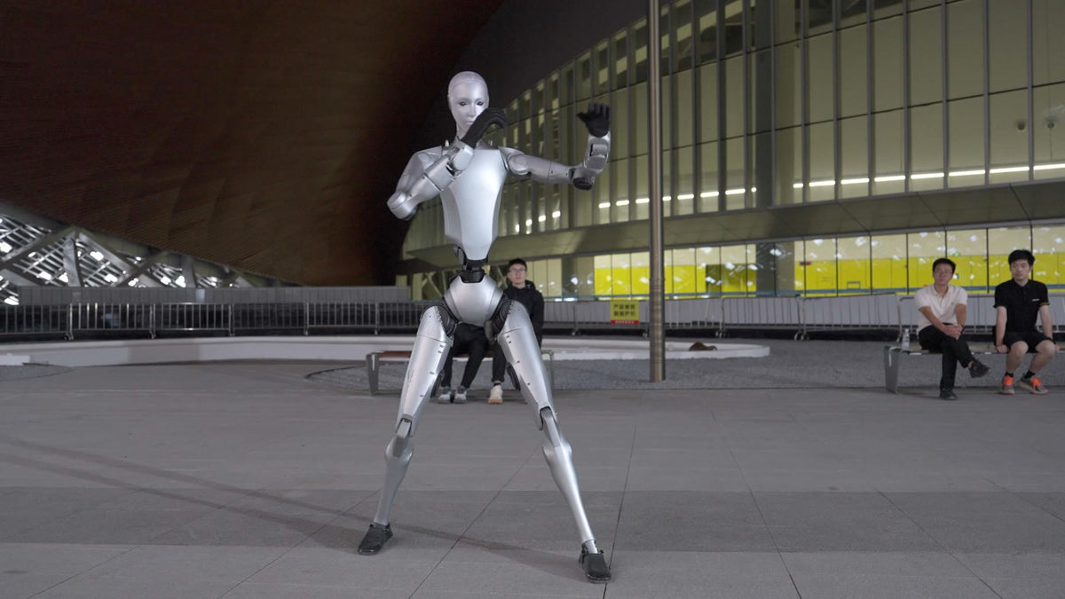 Unitree H2 humanoid robot moving outdoors in front of a stadium