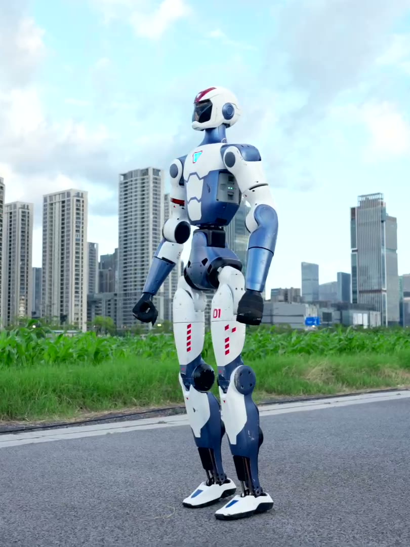 Unitree R1 humanoid robot standing on a road against a city skyline