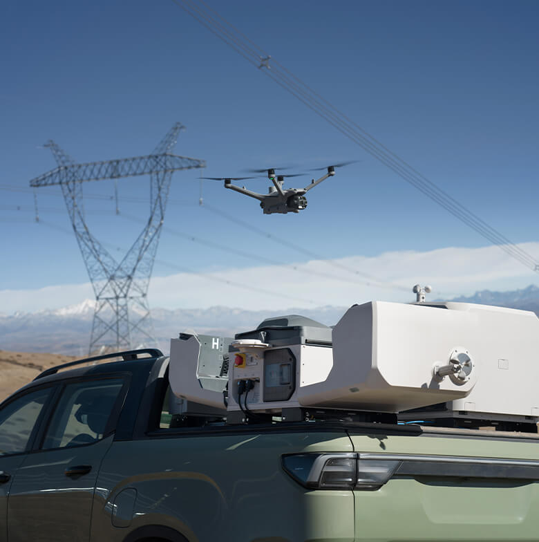 DJI Dock 3 mounted in a pickup truck bed with the aircraft airborne near transmission lines
