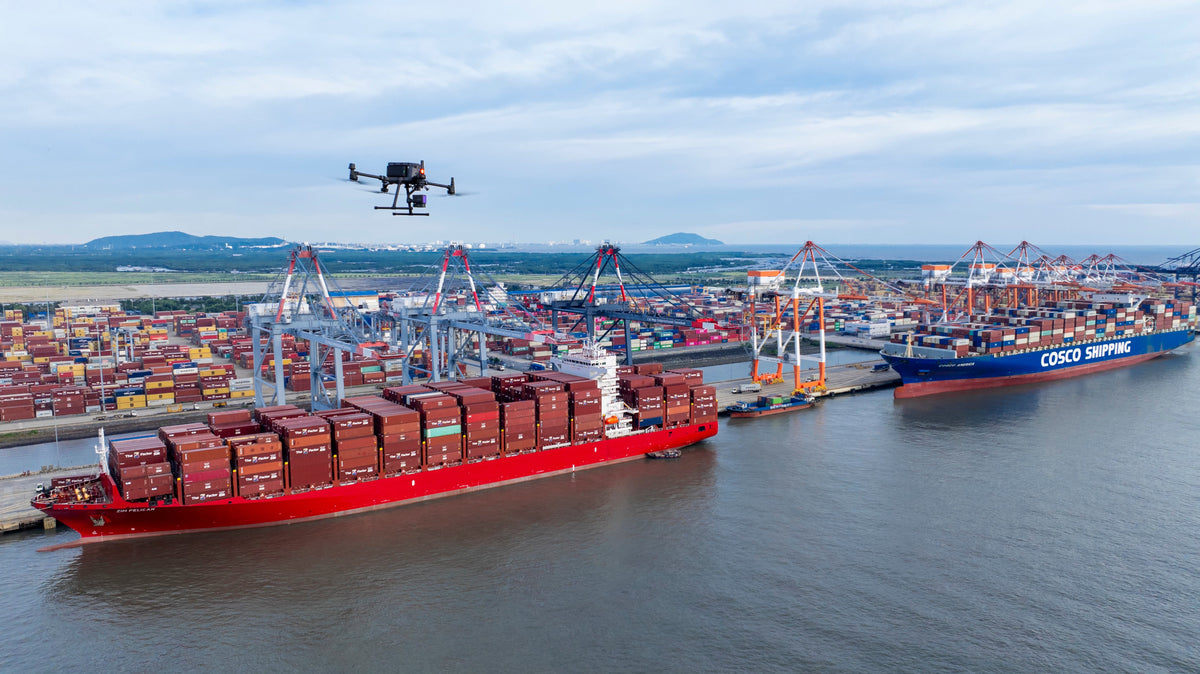 DJI Matrice 300-series enterprise drone with a LiDAR payload flying a survey over a container port