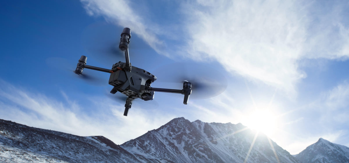 DJI Matrice 30 series drone flying over snow-covered mountains, the terrain where thermal search and rescue drones earn their keep