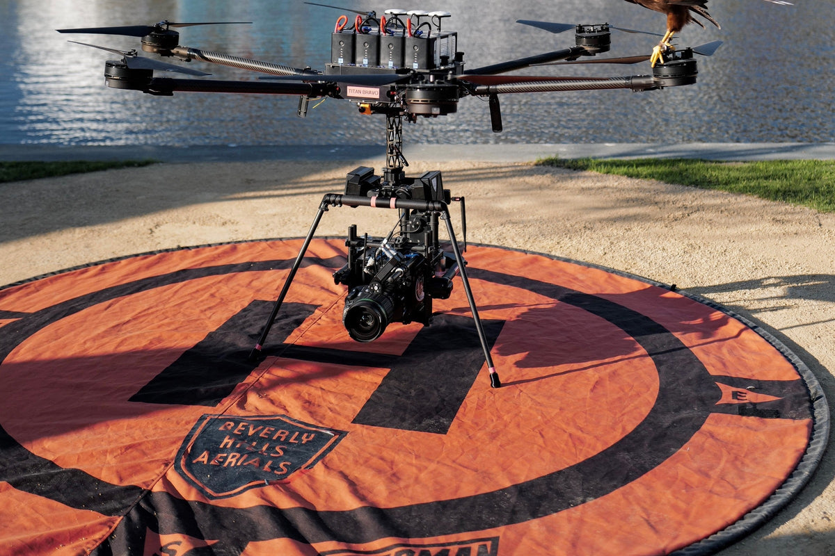 Heavy-lift cinema drone on a Hoodman weighted landing pad at a stadium