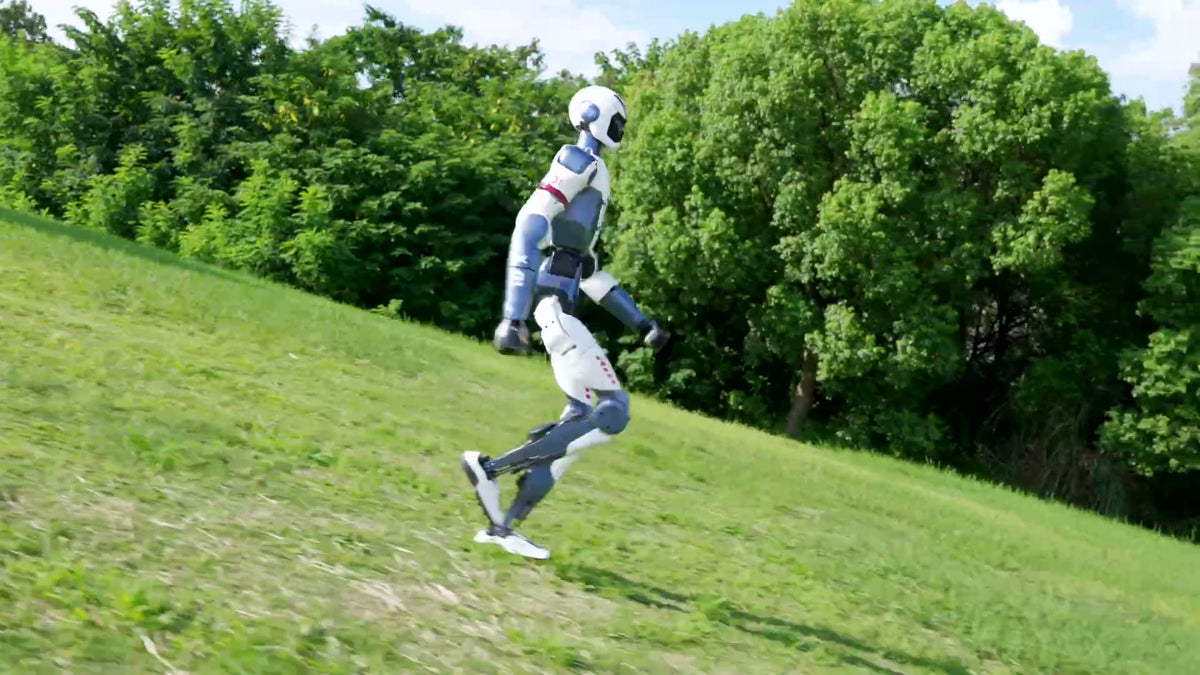 Unitree R1 humanoid robot running up a grass slope